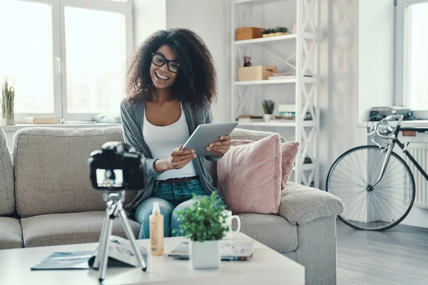 魅力的な若いアフリカの女性は ソーシャルメディアビデオを作りながら デジタルタブレットや笑顔を指しています — ストック写真