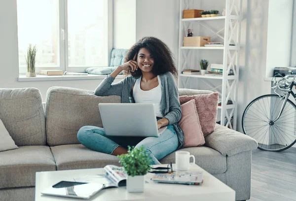 Mulher Africana Bonita Roupas Casuais Usando Laptop Sorrindo Enquanto Descansa — Fotografia de Stock