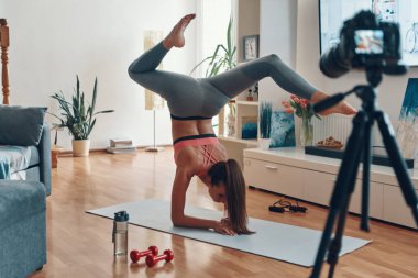 Spor elbiseli esnek genç bir kadın sosyal medya videosu çekerken el ele tutuşuyor.           