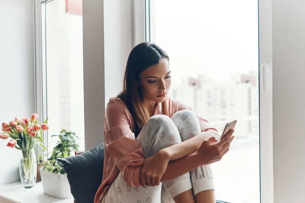 Mujer Joven Perezosa Pijamas Acogedores Usando Teléfono Inteligente Mientras Descansa —  Fotos de Stock