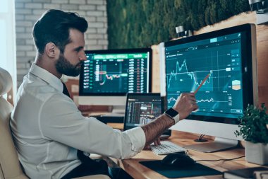 Resmi görevdeki konsantre genç adam ofiste otururken bilgisayar kullanarak çalışıyor.