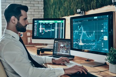 Resmi olarak meşgul genç bir adam ofiste otururken bilgisayar kullanarak çalışır.