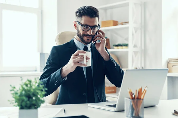 Şık Takım Elbiseli Mutlu Genç Adam Ofiste Otururken Telefonla Konuşuyor — Stok fotoğraf