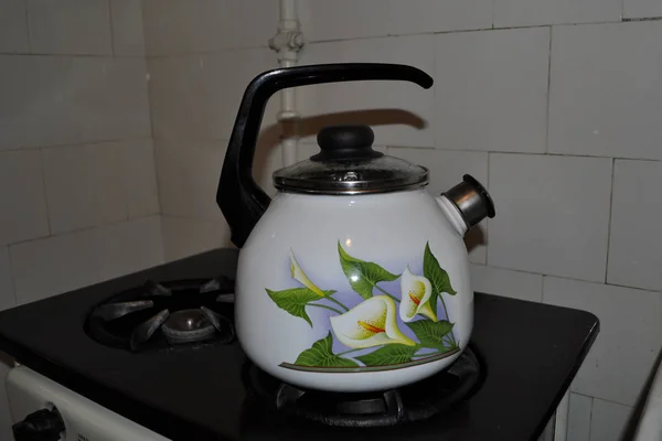 Sobanın üzerinde zambaklar olan çaydanlık.