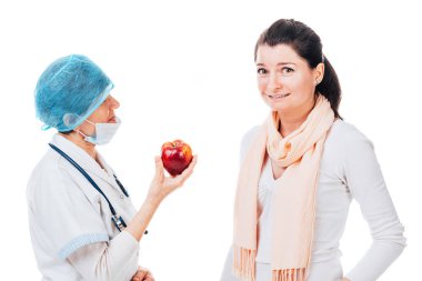 Doktor, beyaz tenli güzel bir kadına kırmızı elma veriyor.
