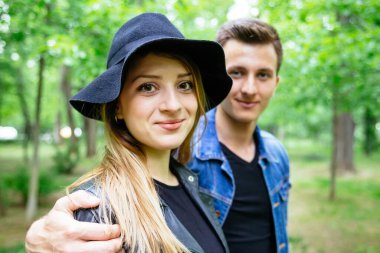Parkta yakışıklı erkek arkadaşı tarafından kucaklanırken gülümseyen güzel sarışın kadın..