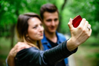 Parkta selfie çeken genç bir çiftin bulanık pozu. Telefona odaklan..