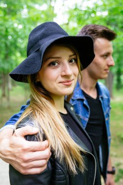 Erkekler ona sarılırken kameraya gülümseyen genç bir kadının profili. 