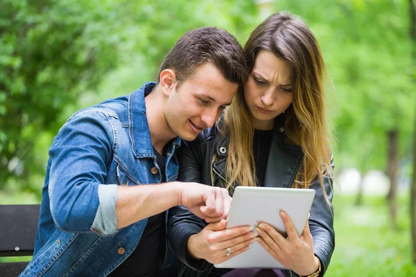 Paar Auf Bank Park Beim Versuch Mit Digitalem Tablet Lernen Stockbild