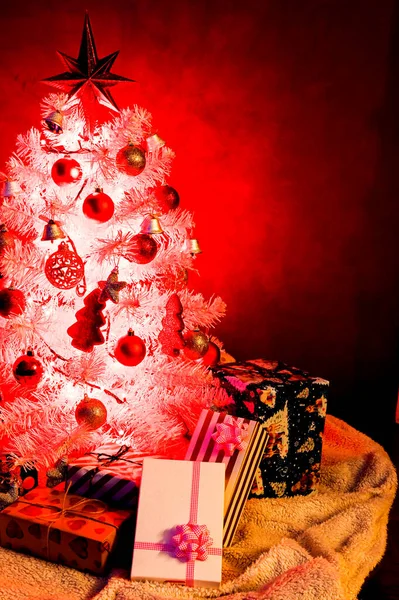 Beyaz Noel ağacı, kırmızı süslemeli ve noel ışığıyla