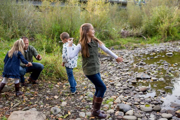 Frères et sœurs jetant des pierres dans la rivière ensemble — Photo