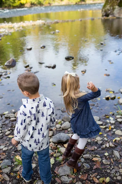 Rodzeństwo razem rzucania kamieniami w rzece — Zdjęcie stockowe