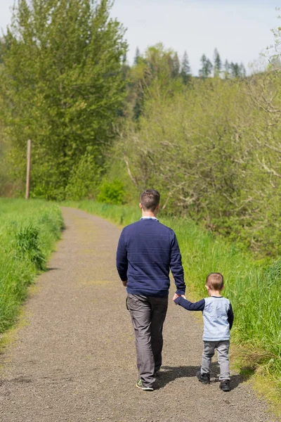 Отец и сын идут, держась за руки — стоковое фото
