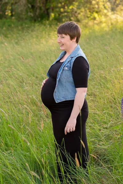 Mujer embarazada en un campo para las fotos de maternidad — Foto de Stock