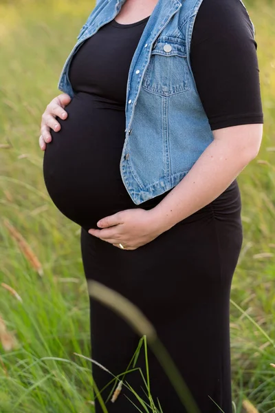 Беременная женщина в поле для материнских фотографий — стоковое фото