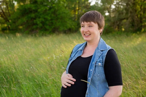 Mujer embarazada en un campo para las fotos de maternidad — Foto de Stock