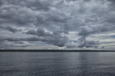 Deniz ve ormanın üzerinde koyu gümüş bulutlar