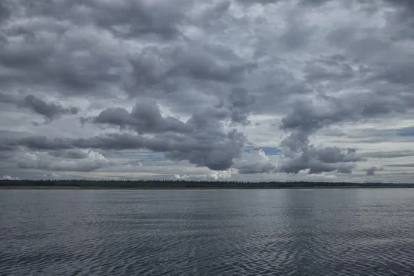 Deniz ve ormanın üzerinde koyu gümüş bulutlar