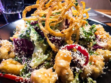 Kızarmış soğan halkalarıyla salatayı karıştır.