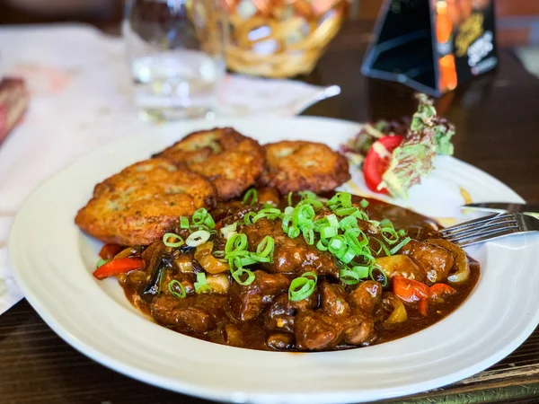 traditional czech goulash dish with fried potatoes & spring onion