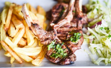 Lezzetli ızgara kuzu budu patates kızartması, pesto sosu ve marul karışımı.
