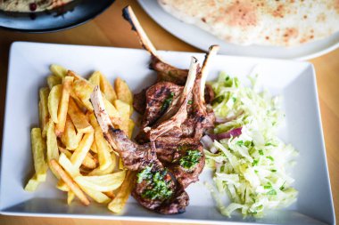 Lezzetli ızgara kuzu budu patates kızartması, pesto sosu ve marul karışımı.