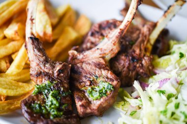 Lezzetli ızgara kuzu budu patates kızartması, pesto sosu ve marul karışımı.