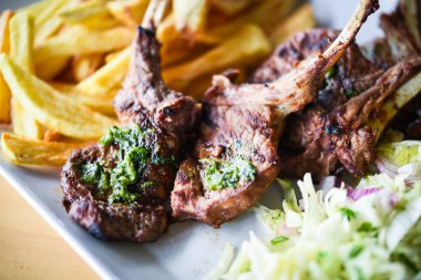 Lezzetli ızgara kuzu budu patates kızartması, pesto sosu ve marul karışımı.