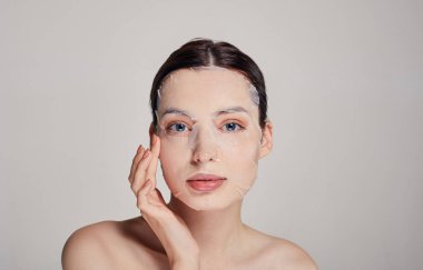 Mavi gözlü, dolgun dudaklı, nemlendirici maske takan, dokunaklı yüzlü güzel, sevimli bir kız. Koyu renk. Dümdüz. Uzayı kopyala Spa, kozmetoloji.