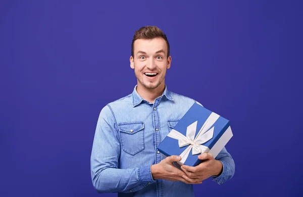Joyful happy guy with gift looking straight and smiling.
