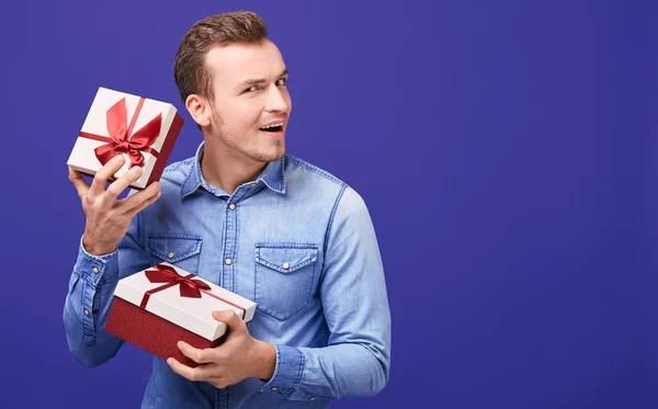 Joyful happy young man listens what rattles in a present.