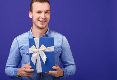 Joyful happy young man looking straight and winking .