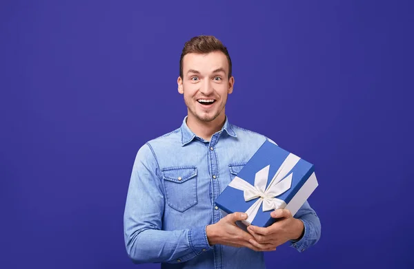 Joyful happy guy with gift looking straight and smiling.