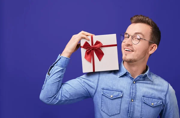 Jovem sorridente de camisa jeans com presente na mão. Natal, Ano Novo, Dia dos Namorados . — Fotografia de Stock