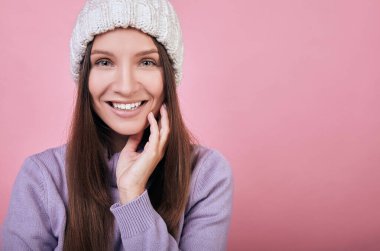 Nazik bayan beyaz örgü bir şapka ve zarif bir mor süveter giyiyor.