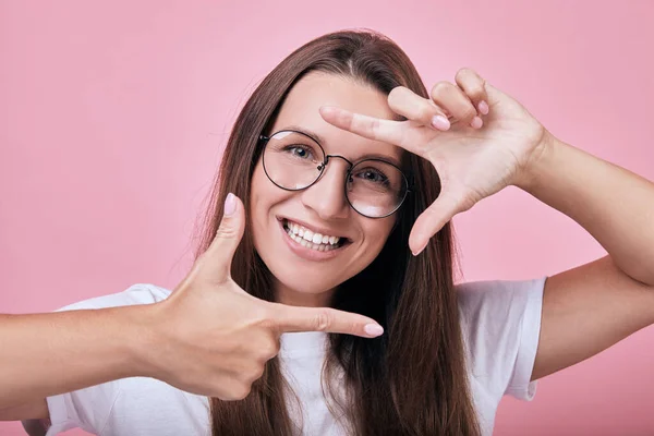 Smiling woman shows frame borders for photo with her hands — Stock Photo, Image