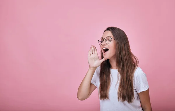 Joyful girl in round glasses put one hand to her mouth as if screaming — Stock Photo, Image