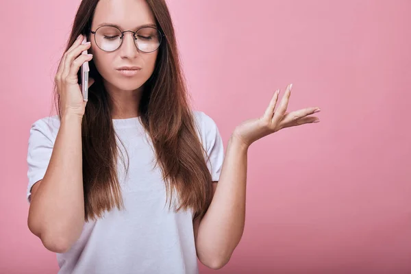 Charmantes Mädchen, das auf einem Handy spricht und an ihrer linken Hand in der linken Seite zeigt — Stockfoto