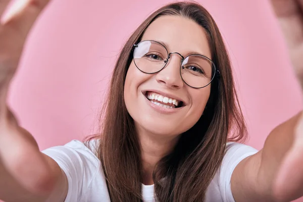 Cute happy woiman in glasses smiling broadly and takes a selfie — Stock Photo, Image