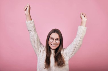 Örgü süveter giymiş güzel bir kız. Gülümsüyor, zaferle seviniyor.