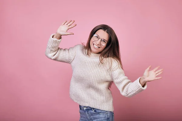 Nettes lustiges Mädchen in Pullover und Brille hüpft und lächelt — Stockfoto