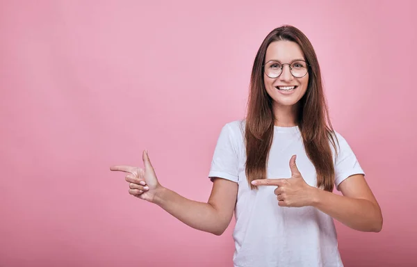 Smiling lady shows forefingers of both hands to the side. — Stock Photo, Image