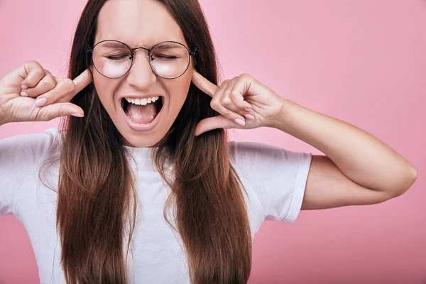 Komische verrückte Mädchen bedeckte ihre Ohren mit den Zeigefingern beider Hände und schrie laut — Stockfoto