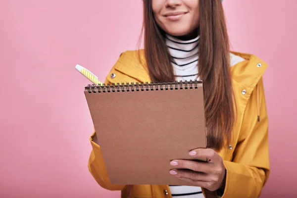 Cool leende student stående med en anteckningsbok och penna i händerna — Stockfoto