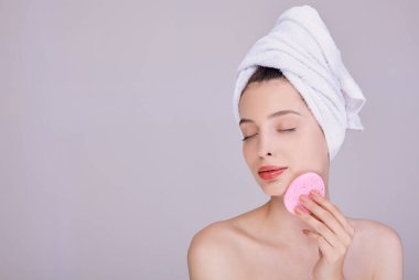 Şehvetli kız yüzünün yanında sünger tutuyor..