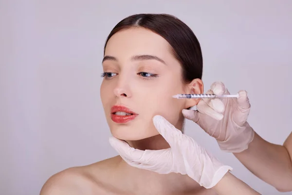 Um cosmetologista faz procedimentos anti-envelhecimento para menina rosto . — Fotografia de Stock