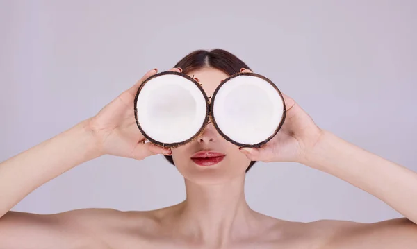 A young girl holds coconuts in her hands like glasses. — Stock Photo, Image