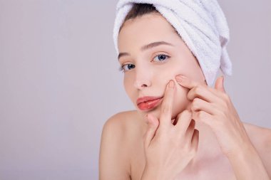 A young girl cleans pores on her cheek.
