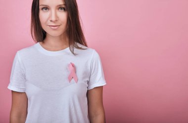 Göğsünde pembe kurdele olan tatlı sakin kız.