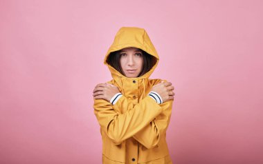 Kapüşonlu güzel, üzgün kız yağmurluğu dondu ve titriyor.